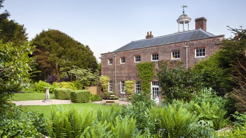 A brick country house in the midst of green and well kept gardens